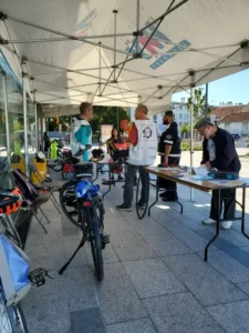 Membres de Mieux se Déplacer à Bicyclette échangeant avec des passants lors d'un atelier réparation de vélo sur le parvis de la ligne 14 du métro à L'Haÿ-les-Roses