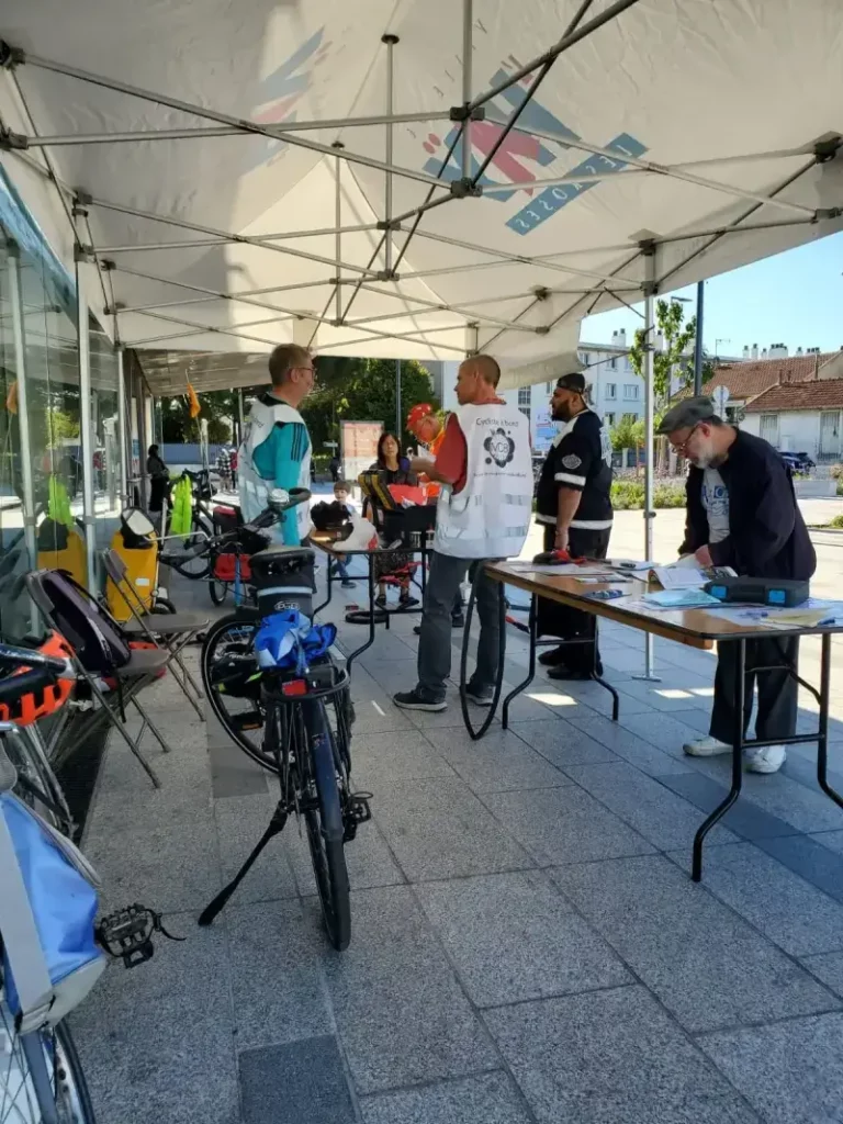 Membres de Mieux se Déplacer à Bicyclette échangeant avec des passants lors d'un atelier réparation de vélo sur le parvis de la ligne 14 du métro à L'Haÿ-les-Roses
