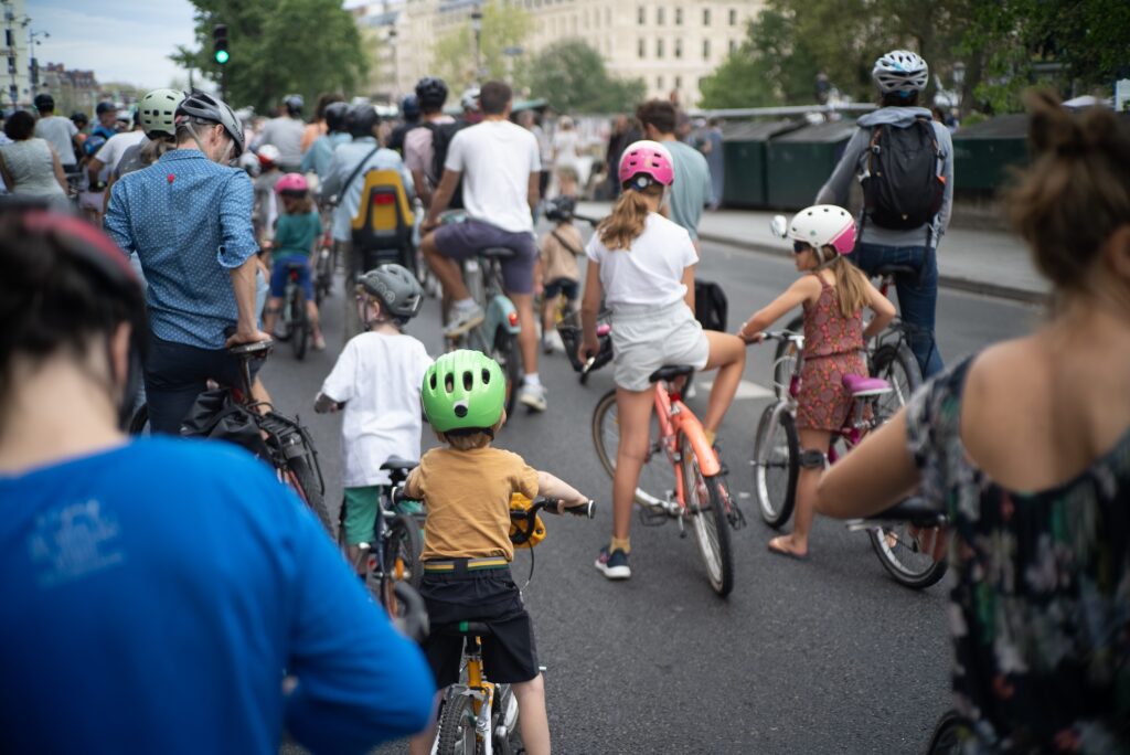 Plusieurs enfants à vélo, de dos, sur les quais hauts de la rive gauche de Paris, lors d'un événement festif encadré