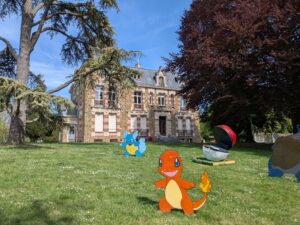 Château du Val des Dames à Gretz-Armainvilliers. Le bâtiment est encadré de deux arbres majestueux. Au premier plan, des Pokémons disposés dans l'herbe.