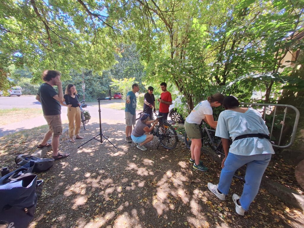 Personnes réparant des vélos en extérieur sous des arbres;